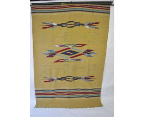 A vintage Navajo Indian wool blanket in traditional design with open-work, maize coloured ground with deep red/blues/grey, 19