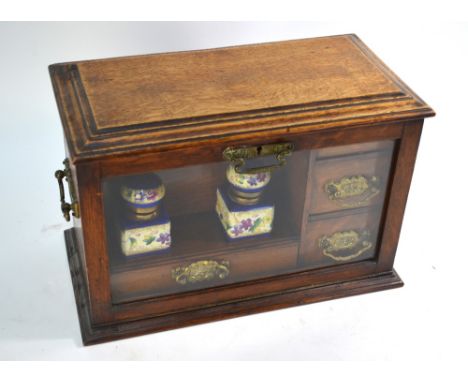 An oak writing box fitted with stationery rack, ceramic inkwells and bow and four drawers enclosed by glazed fall front, 36 c