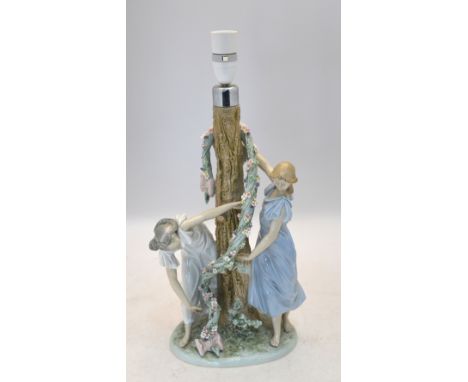 A Lladro lamp base with two maidens decorating a tree with a floral garland, 1607 impressed to base, 1988, &nbsp;35.5 cm high