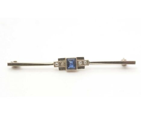 An Art Deco sapphire and diamond bar brooch, the step cut sapphire flanked by two round brilliant cut diamonds, in white gold