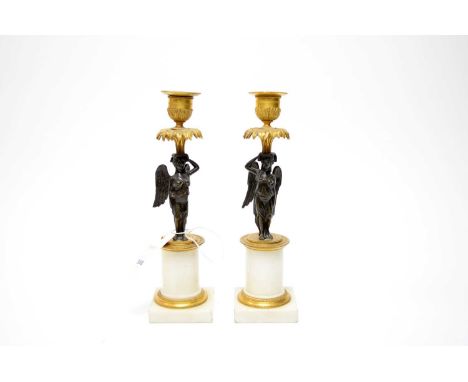 A pair of French Neoclassical gilded bronze candlesticks, each modelled with a winged maiden in draped robes, supporting a gi