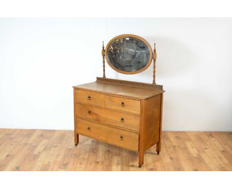 An 20th century oak dressing chest, the oval mirror with finial supports and Vitruvian scroll motifs, over two short and two 