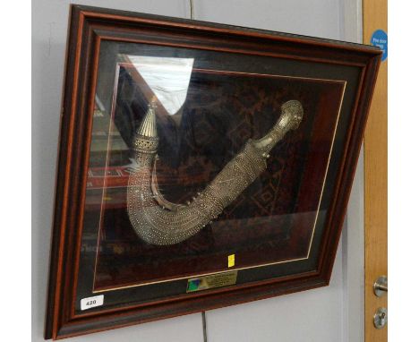 An Arab Jambiya dagger, with ornately tooled white metal hilt and scabbard, in glazed display case, 57 x 48cms high; together