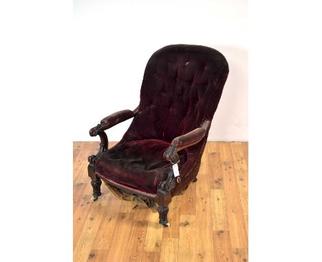 A Victorian walnut button back chair, upholstered in red velvet, the scrolled elbow rests, overstuffed seat, raised on acanth