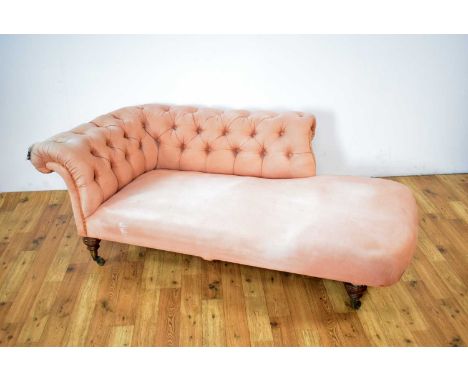 Howard &amp; Sons Ltd: A Victorian chaise longue upholstered in salmon pink fabric, the button back and side rest, raised on 