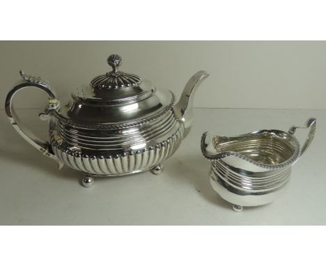 A George III silver teapot of oval form the hinged lid with decorative finial, gadroon edging, semi fluted body and on four b