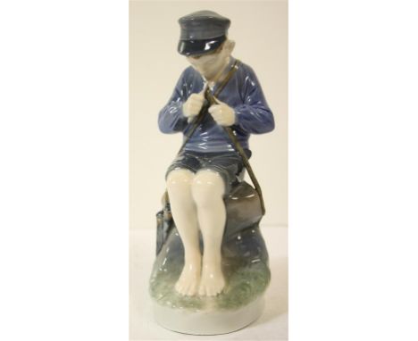 A Royal Copenhagen porcelain figurine of a boy seated, sharpening a stick.  18 cm high. 