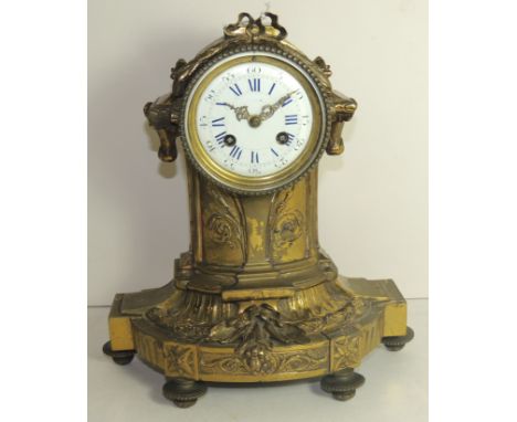 A late 19th Century mantel clock the circular white enamel dial with blue Roman numerals and black Arabic minute numerals, ho