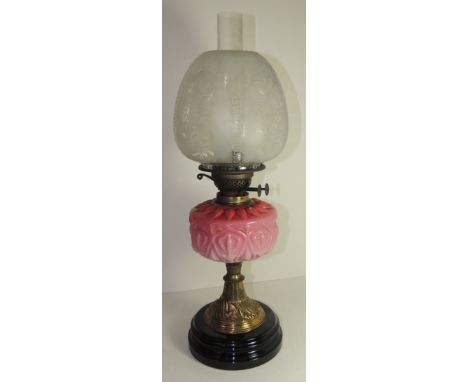 A Victorian oil lamp with etched glass shade, moulded pink glass reservoir, brass pedestal and on stepped black glass base