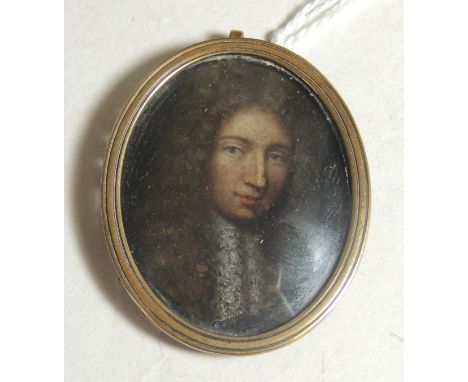 An early 19th Century miniature painted portrait of a gentleman wearing a long curled wig, oil on copper, in gold metal frame