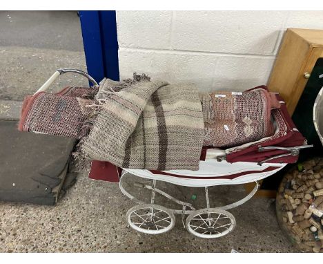 Vintage dolls pram together with a patterned rug and a blanket