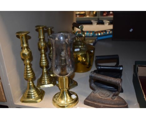 Two pairs of brass candlesticks with an oil lamp, stove kettle and three irons.