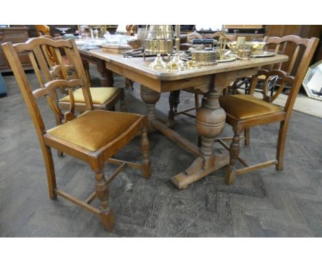 A 1930's light oak draw leaf dining table on cup and cover supports and four matching chairs 