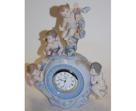 A Lladro porcelain cased mantel clock, surmounted by cherubs, printed mark verso and impressed 5973, boxed