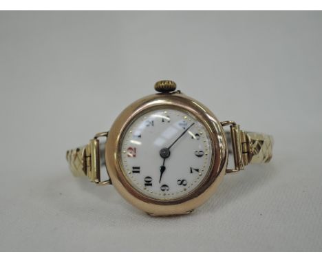 A lady's vintage 9ct rose gold wrist watch having an Arabic numeral dial with gilt minute dots on a white enamel face on a la