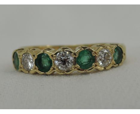 A lady's 18ct gold eternity ring having four emeralds interspersed by three diamonds in a collared mount,  size R