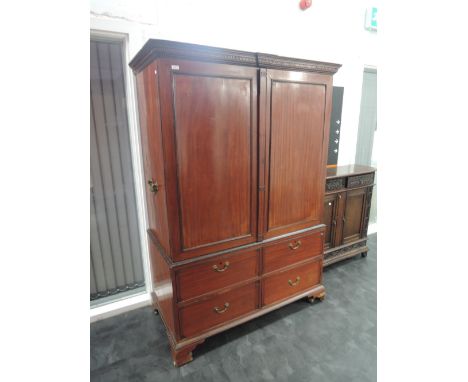 A late Victorian/Edwardian mahogany linen press having double cupboard over four short drawers and bracket feet