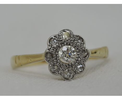 A lady's dress ring having a diamond daisy cluster in an illusionary setting on a yellow metal loop stamped 18ct & plat,  siz