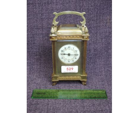 An early 20th century French brass carriage clock of traditional design by R & Co having ornate decoration and circular ename