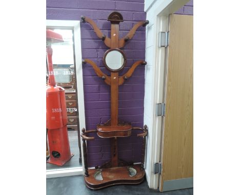 A late Victorian mahogany hall stand of tree form having circular mirror and branch lugs over shape glove box and stick secti