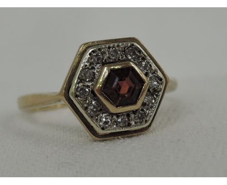 A lady's dress ring having a central fire opal style stone with diamond chip surround in a hexagonal setting on a 9ct gold lo