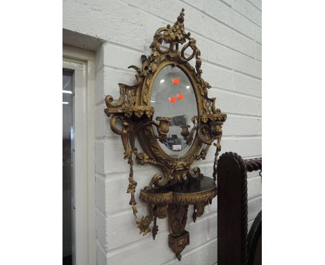 A 19th century gilt plaster mirror in the Rococo style of scroll fret, ledge and sconce design