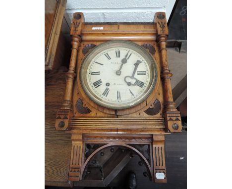 A late Victorian golden oak case wall clock in the Gothic style having circular Roman numeral dial for T & E Rhodes, Kendal