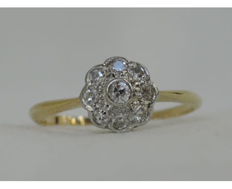 A lady's dress ring having a diamond daisy cluster in a collared mount on a yellow metal loop stamped 18ct & plat,  size M