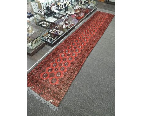 An early 20th century carpet runner of turkmen design having red ground, 151'x29'