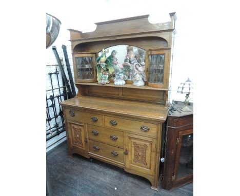 A late Victorian golden oak full height sideboard having ledge mirror back, flanked by  convex display cupboards, over carved