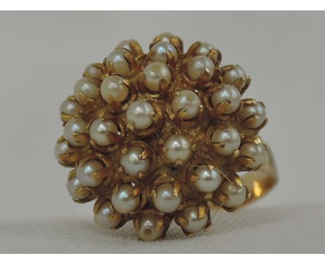 A lady's dress ring having a domed seed pearl open cluster on a yellow metal loop stamped 18, (loop split), approx 8.7g & siz