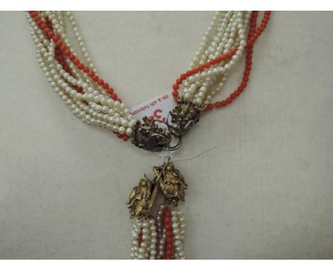 A ten strand twist seed pearl and coral necklace having silver gilt clasps in the form of Chinese dragons having ruby set eye