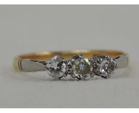 A lady's dress ring having a trilogy of diamonds, approx 0.2ct in a raised claw mount on a yellow metal loop stamped 18ct,  s