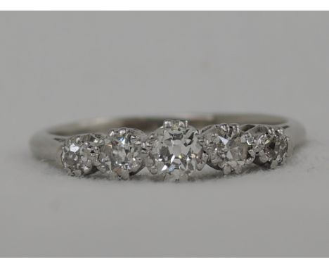 A lady's dress ring having five graduated diamonds in claw mount on a white metal loop stamped plat, size M