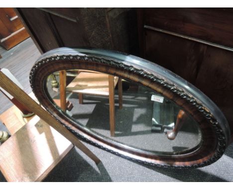 An early 20th century oval wall mirror of simulated rosewood design
