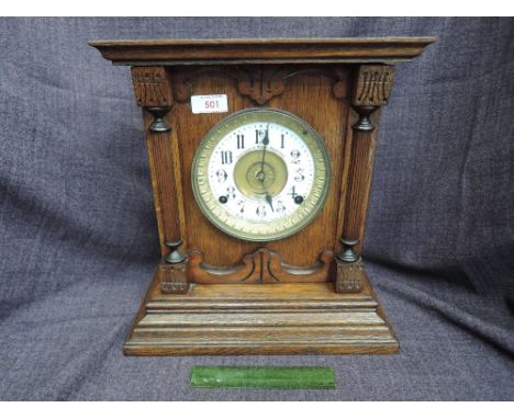 An Edwardian oak cased mantel clock with circular Roman numeral dial and English patent automatic alarm