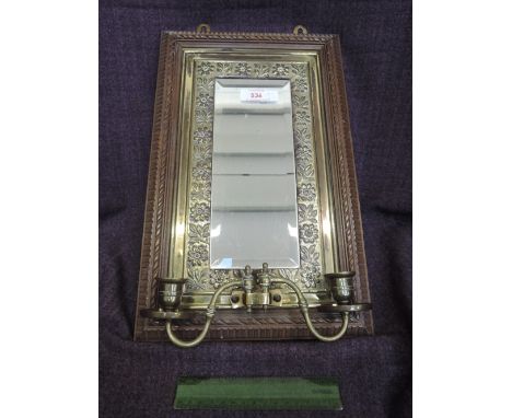 An Edwardian brass and treen wall mirror having foliate decoration and candle sconces