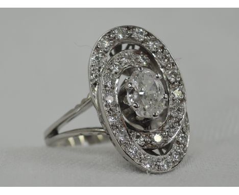 A lady's dress ring having a central oval diamond, approx .75ct within an Art Deco style double diamond set loop to open shou