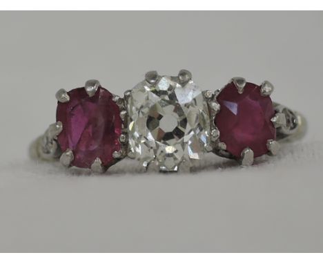 A lady's dress ring having a central diamond, approx .70ct flanked by two rubies, each approx .3ct in a raised claw mount wit