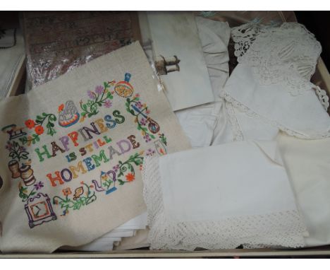 A vintage cream suitcase containing a selection of linen including pillowcases, a cross stitch sampler signed F Braithwaite &