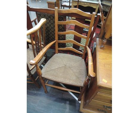 A stained beech frame kitchen armchair having wave ladder back with rush seat and turned frame