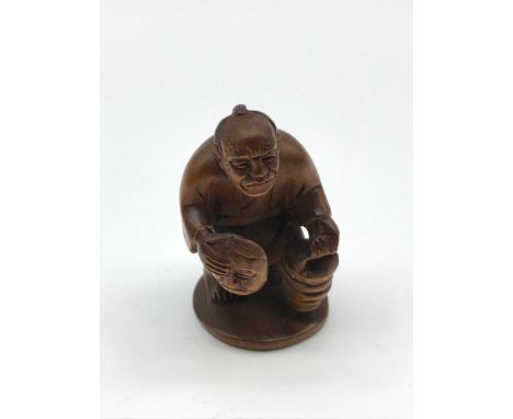 A Japanese hand carved netsuke figure of an elderly gentleman carrying a lantern and a mask. Signed by the artist to the base