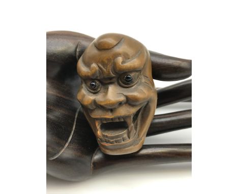 A Japanese hand carved netsuke figure of a traditional Japanese Hannya demon mask. Detailed with black bead eyes and signed t