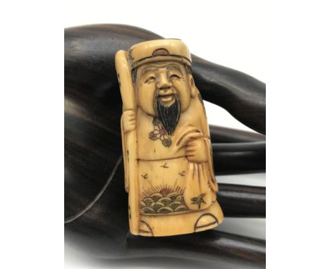 A Japanese hand carved netsuke figure of a elderly Scholar detailed with floral and sun design gown. Signed to the base by th