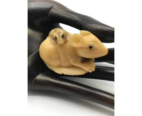 A Japanese hand carved Tagua nut netsuke figure of a Rat carrying a baby rat on its back. Both detailed with black bead eyes 