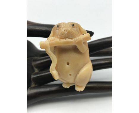 A Japanese hand carved tagua nut netsuke figure of a dog playing a flute. No signature. 