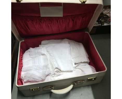 A Vintage travel case containing a collection of vintage table covers and linen 