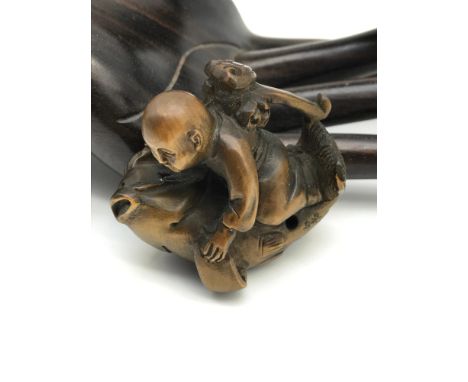 A Japanese hand carved netsuke figure of a monk riding  a large koi carp fish. Highly detailed figure showing black bead eyes