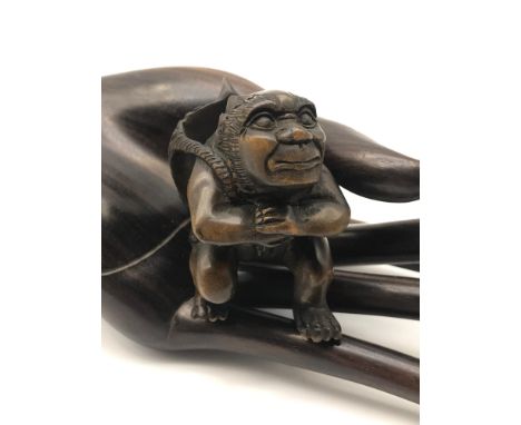 A Japanese hand carved netsuke figure of an Oni Monster carrying a Hannya devil mask. Signed to the base by the artist. 