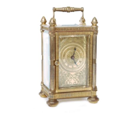 A small early 20th Century brass carriage clock the floral engraved dial enclosed by a glazed door within a pillared case, he